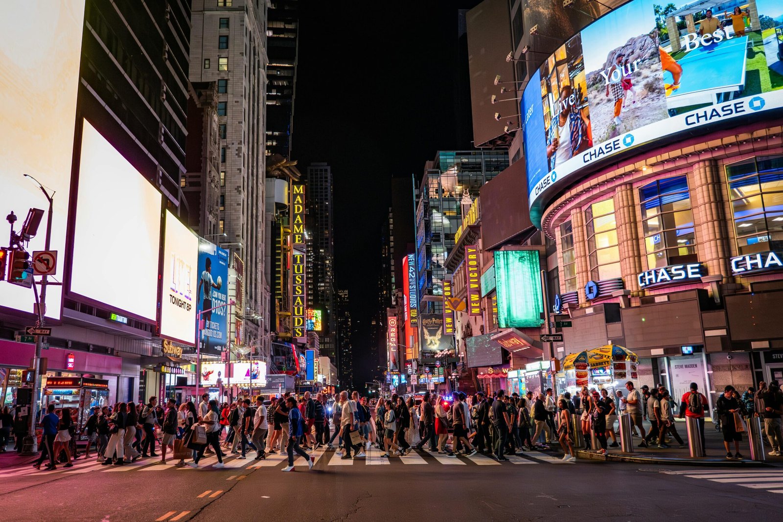 A lively view of Times Square at night with bustling crowds, bright billboards, and iconic landmarks.