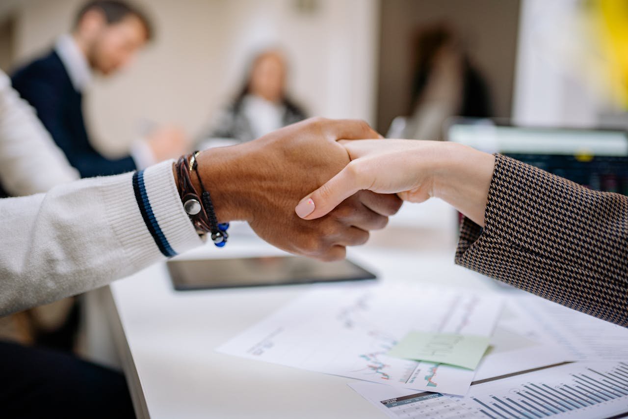 about-me-01 Diverse business professionals exchanging handshake in an office environment, symbolizing agreement.